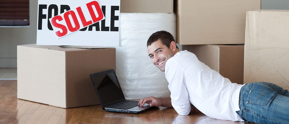 Guy laying on stomach in front of laptop and moving boxes