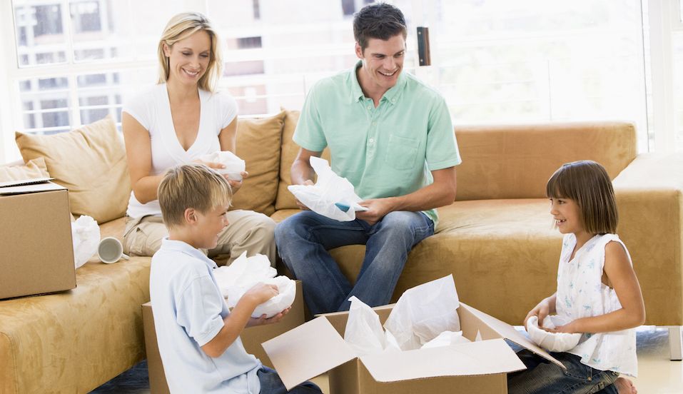 Young family with two kids unpacking boxes