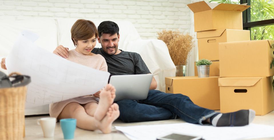 Couple siting with laptop and paperwork next to moving boxes