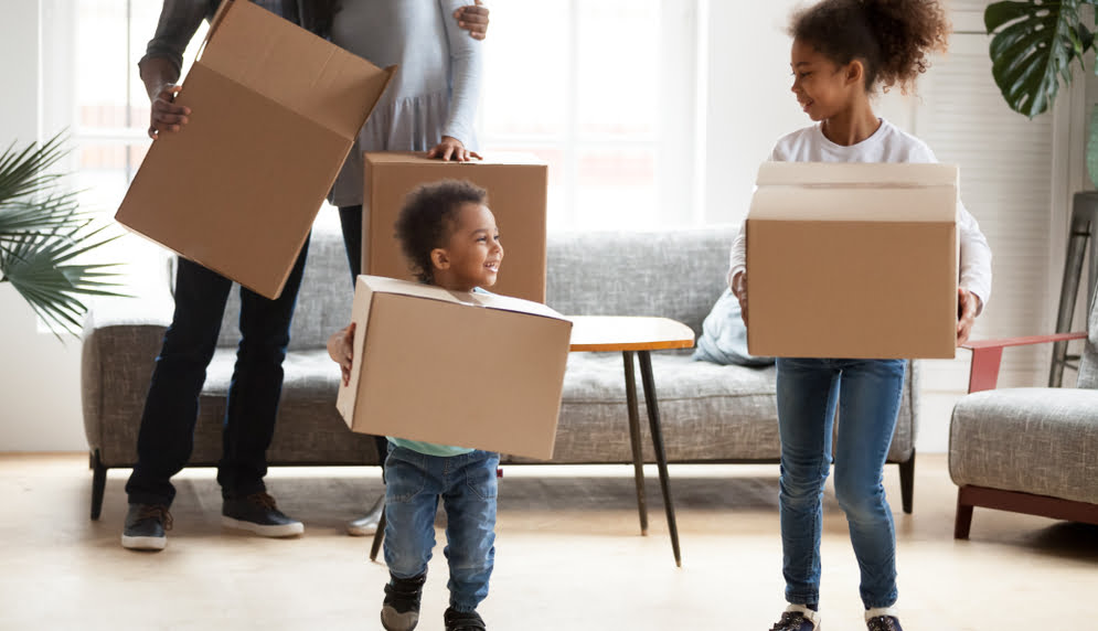 african american small boy and girl moving boxes with parents in background