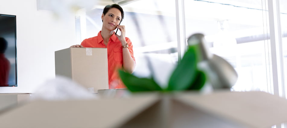 Business woman on the phone in front of moving boxes