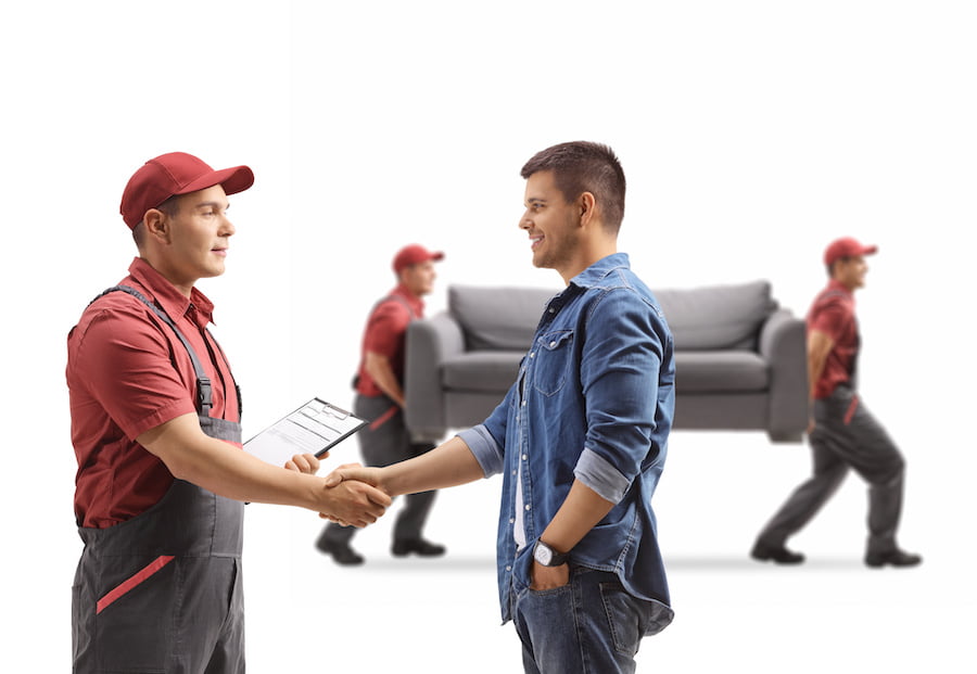 Man shaking hands with a removal guy, movers carrying a couch isolated on white background