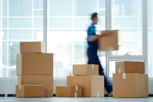 Blurred motion of contemporary worker with packed box walking to new office while delivering it to client