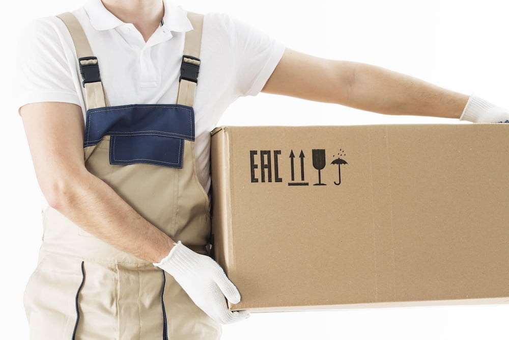 Mover holding in hands cardboard box isolated on white background. Relocation services concept. Loader in uniform with box. Worker in gloves with box for moving