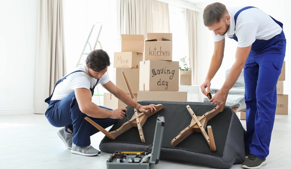 Male movers assembling sofa in new house
