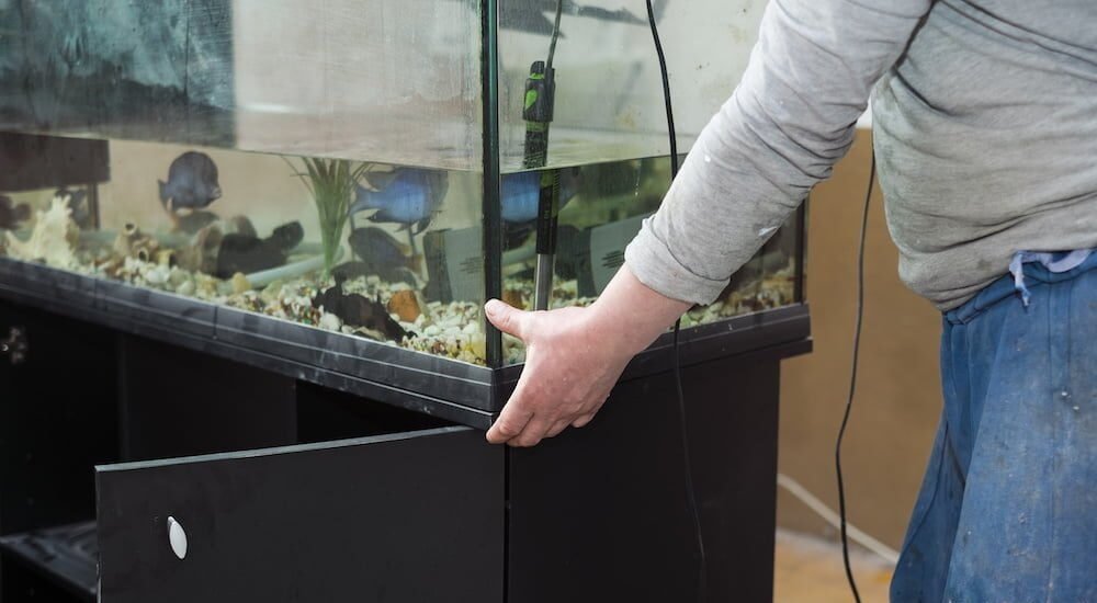 a worker moving a fish tank in a room under renovation