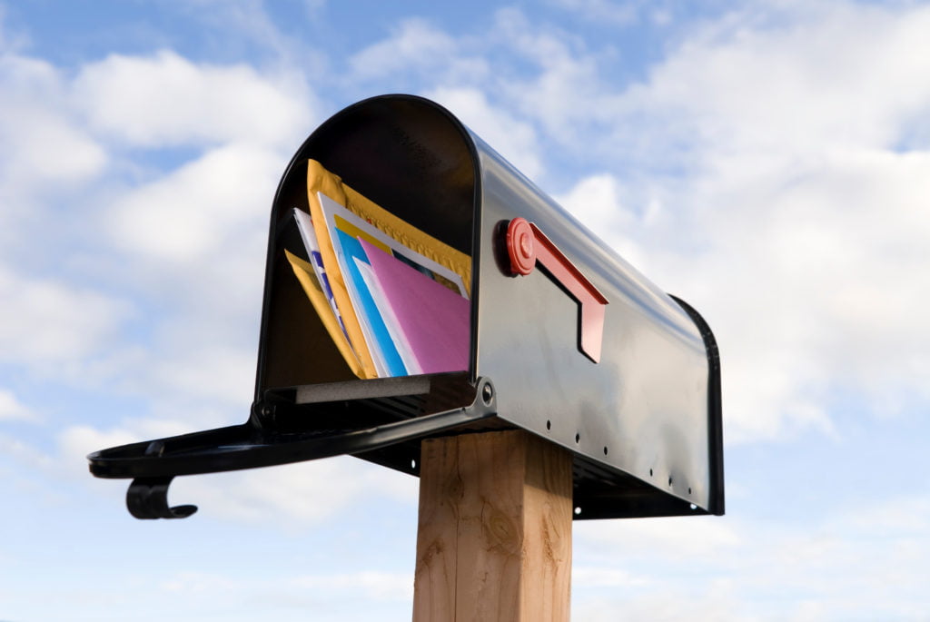 An open freestanding mailbox with colored envelopes inside.