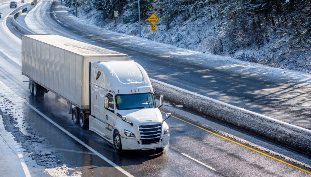 A big rig semi truck driving on a snowy road