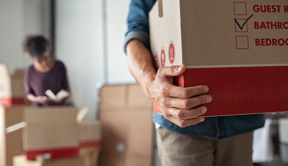 two people carrying moving boxes