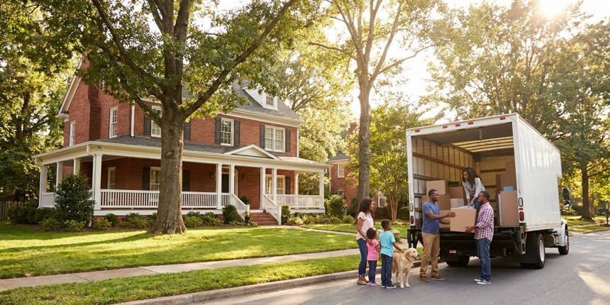 A family unloading a moving truck at their new brick home in a leafy Charlotte North Carolina suburb